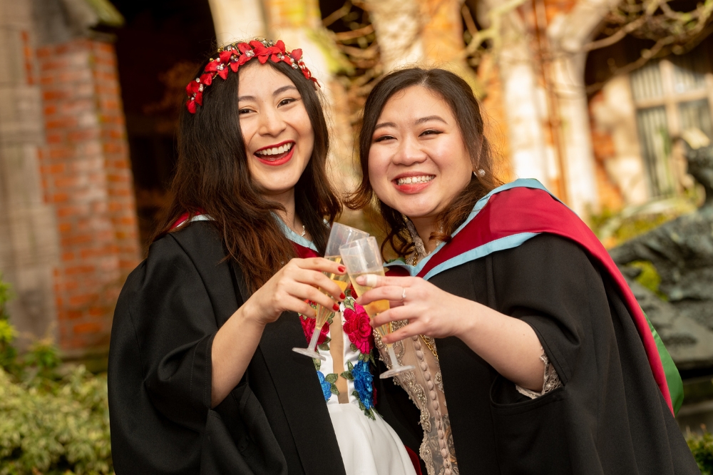 two International students celebrating with sparkling drink at Winter Graduation 2023