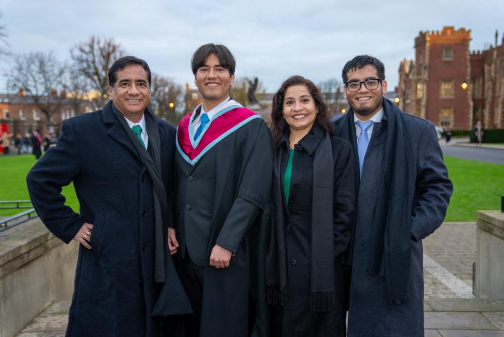 An international student and their family smiling and posing together outside celebrating graduation.