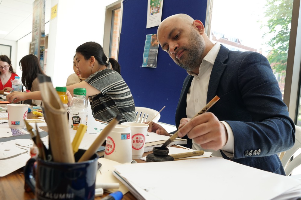staff member trying out traditional Chinese calligraphy at the Language Centre / iRise Summer Social and Wellbeing event, Peter Froggatt Centre