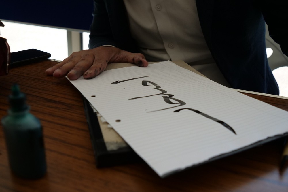 person writing Persian calligraphy