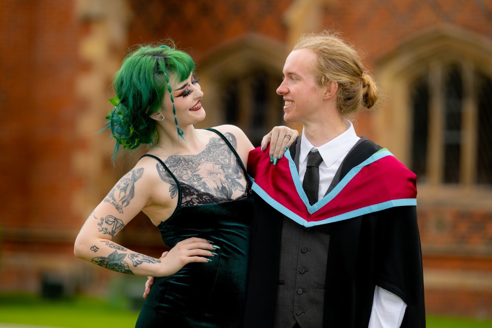 male graduate smiling at graduation guest and girlfriend