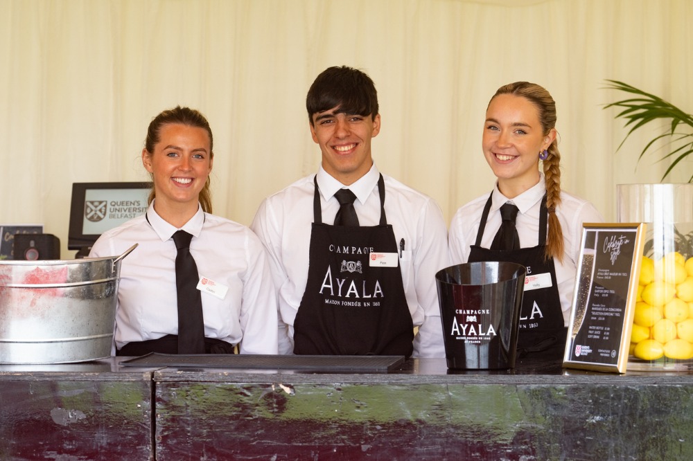 Members of Campus Food and Drink staff smiling at the marquee bar