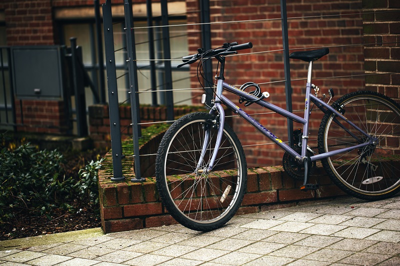 bike resting against fence beside a building