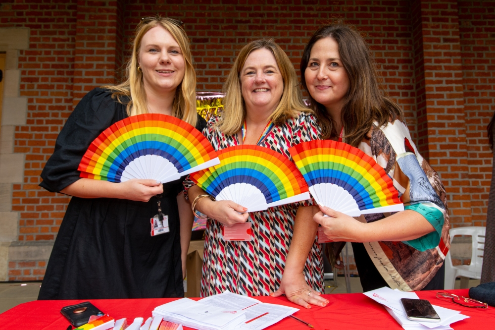 Queen's staff members from the People and Culture Directorate holding rainbow fans at the QUB Pride Picnic 2023