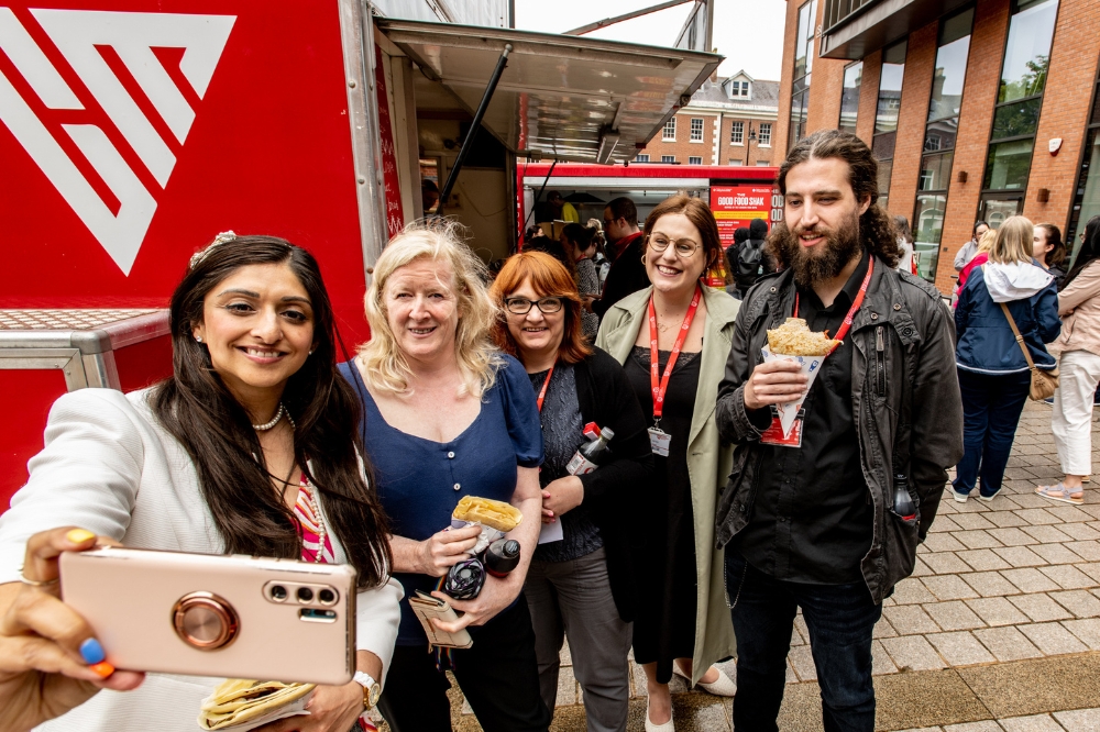 staff members taking a selfie with colleagues beside the crepe van at QUB Pride Picnic 2023 outside the Main Site Tower
