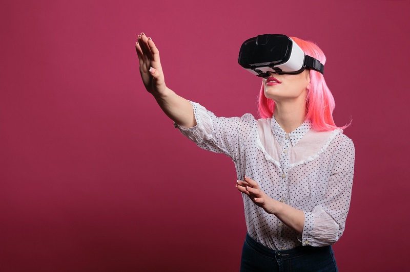 young woman wearing virtual reality / VR headset and reaching out her hands