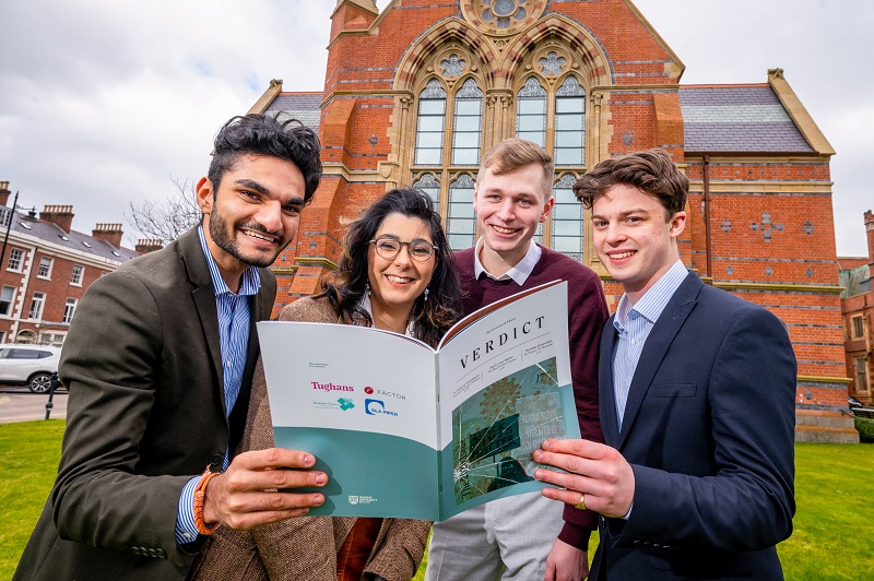 four smiling Queen's Law Society students standing in front of The Graduate School holding a copy of 'The Verdict' publication