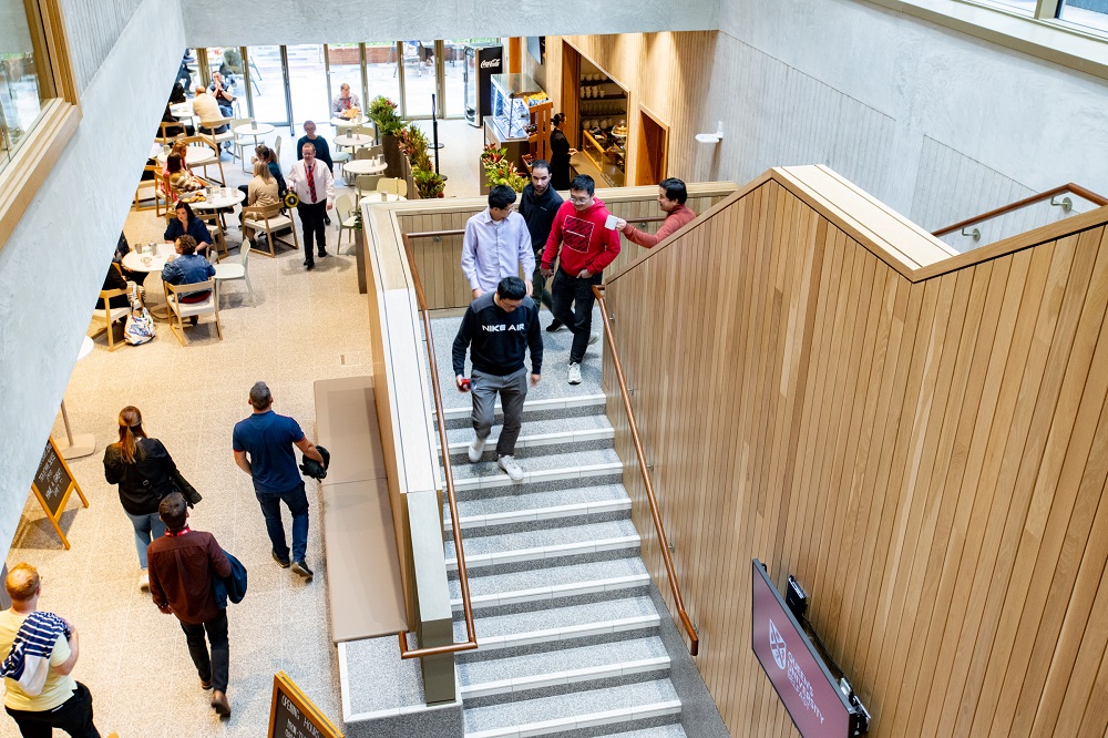 view down steps and into foyer of bustling Queen's Business School from first floor landing