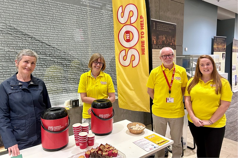 SOS Bus NI volunteers at a coffee table in the McClay Library auditorium