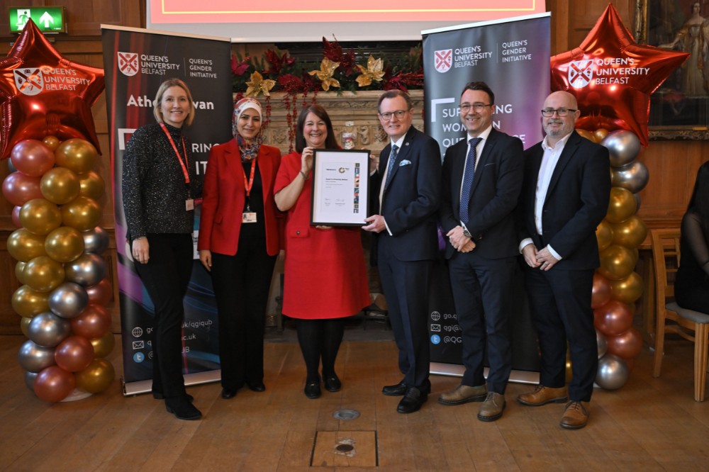 group of people collecting an award in an old wood-paneled event hall with pop-up stands and presentation screen in the background