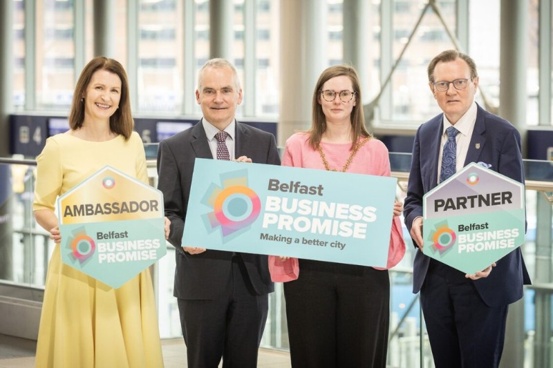 Two men and two women holding one large and two smaller placard which read, respectively: Ambassador, Belfast Business Promise; Belfast Business Promise, making Belfast a better city; and Partner, Belfast Business Promise