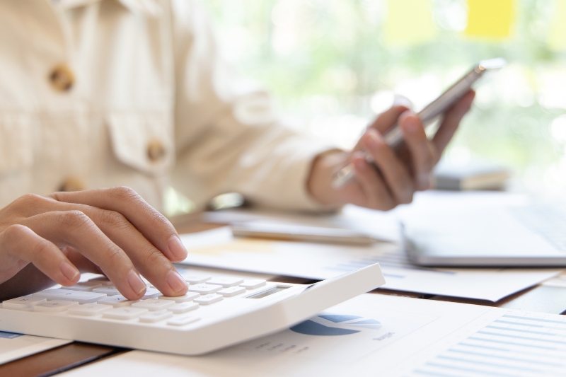 person using calculator and phone at a desk