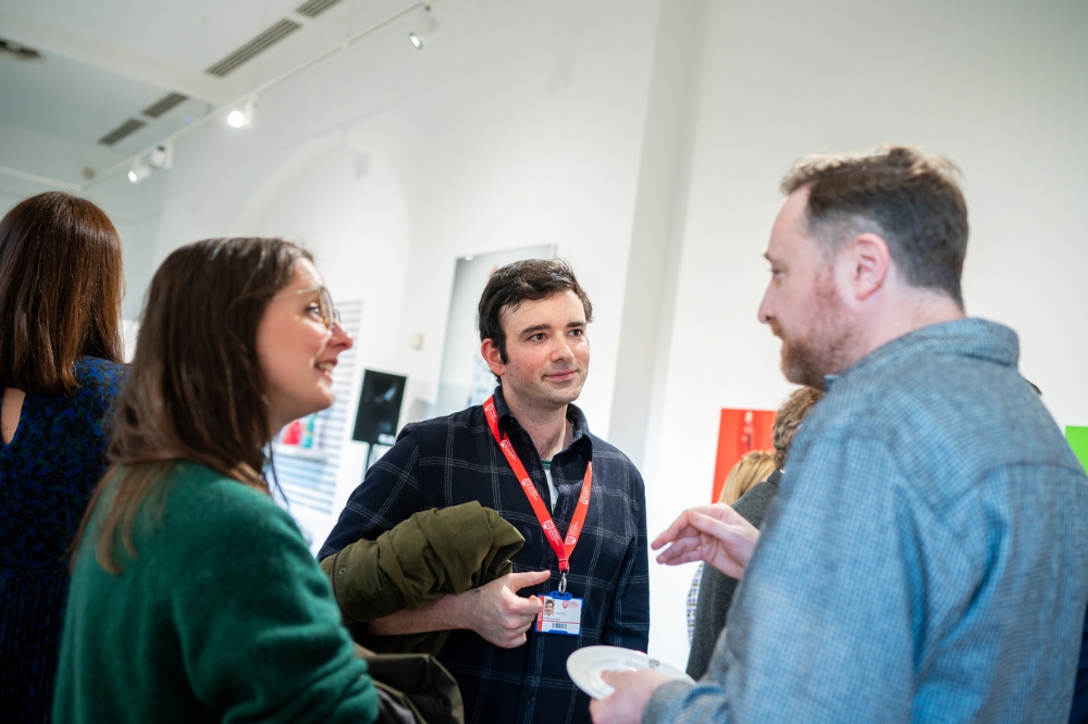 staff members chatting at the launch of Queen's new Staff Network for Promoting Linguistic Diversity and Minority Languages, in the Naughton Gallery
