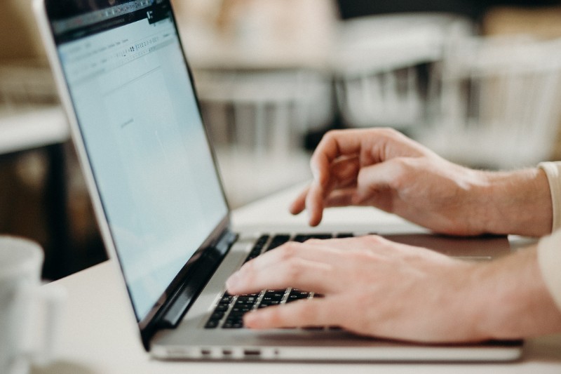 person working on laptop in bright home/office setting