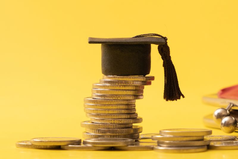 tiny graduation cap sitting on a stack of coins