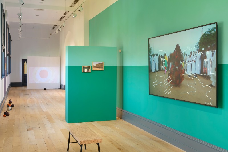 art gallery in green tones showing various wall-mounted exhibits
