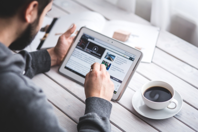 A man engaged in reading a newsletter on his iPad, fully immersed in the latest updates.