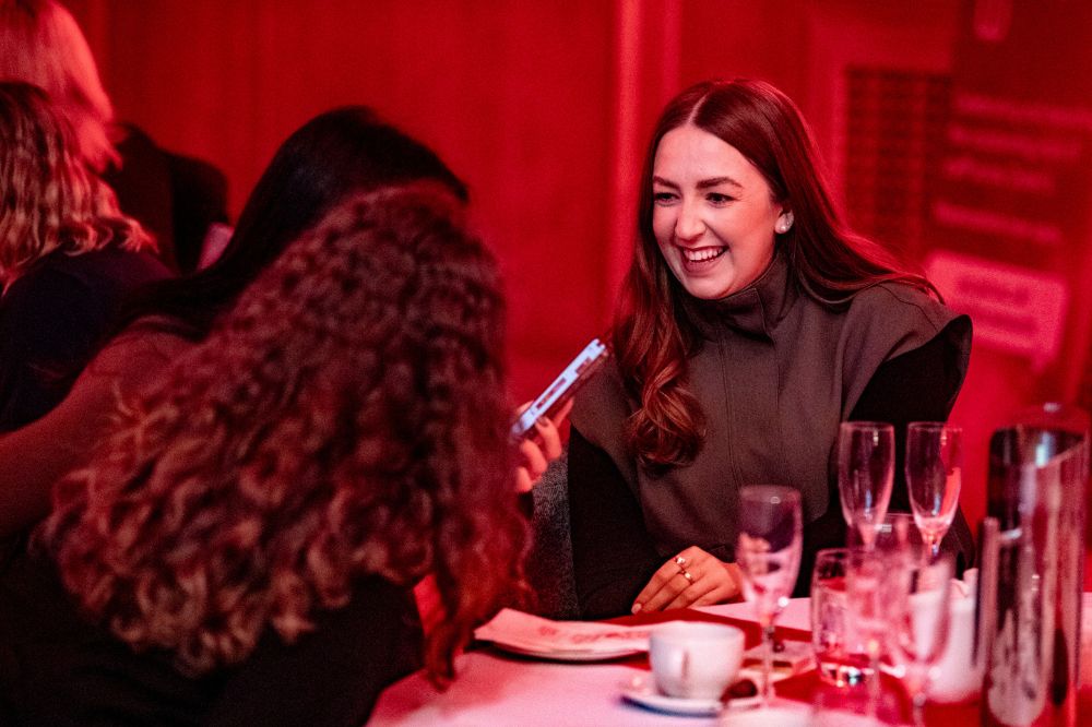 young woman laughing with friends at a set dining table at an indoor event